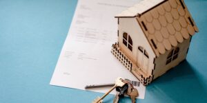 모형 집과 열쇠, 계약서가 놓여있는 사진으로 청약통장으로 집을 계약함을 나타낸다.